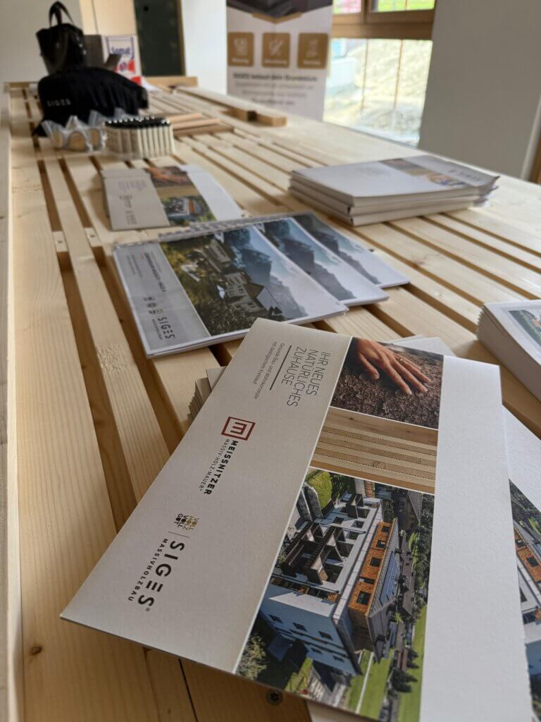 Informationsmaterial zu regionalen Bauprojekten auf Holztisch bei Gewerbeveranstaltung in Piesendorf