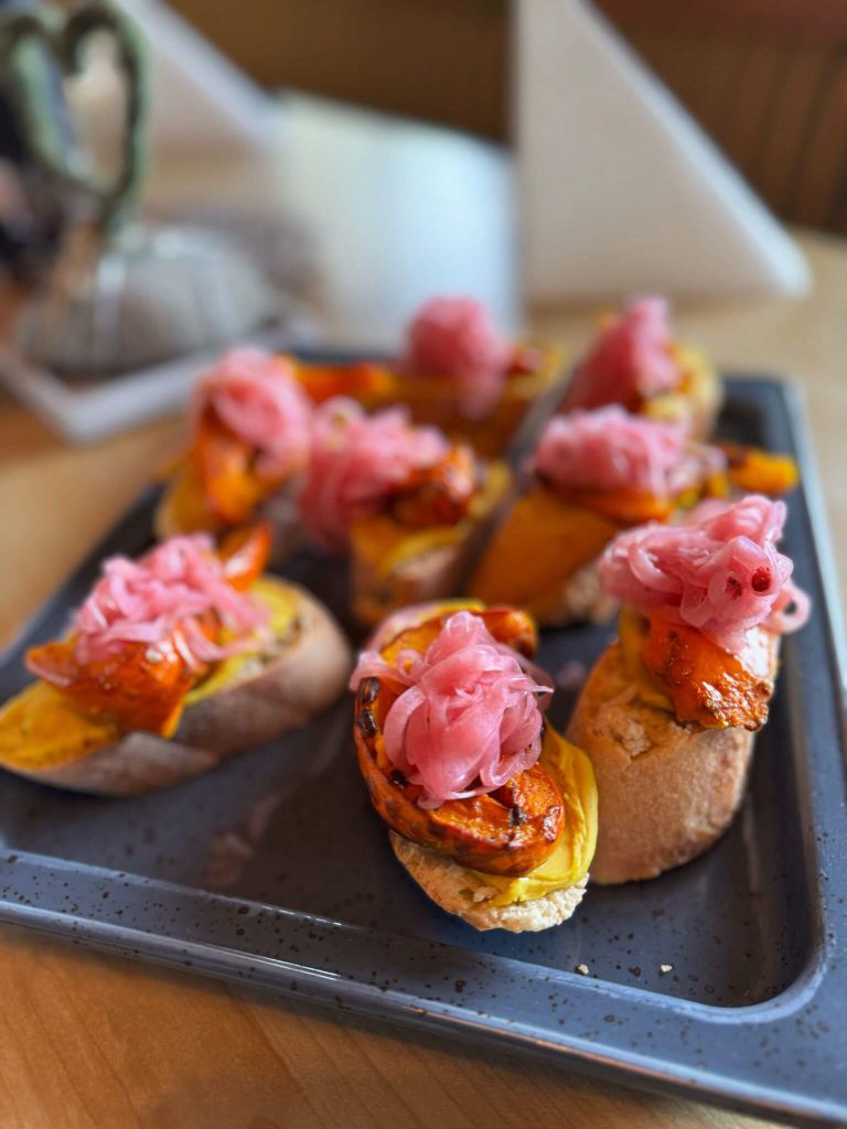 Kleine Brotscheiben mit Kürbis und eingelegten roten Zwiebeln als regionales Catering Piesendorf